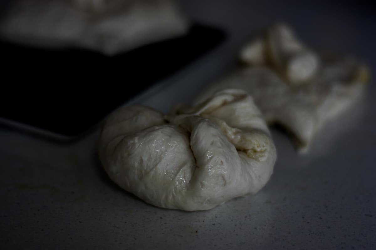 Rough dough sections on a stone work surface ready for rolling into balls.