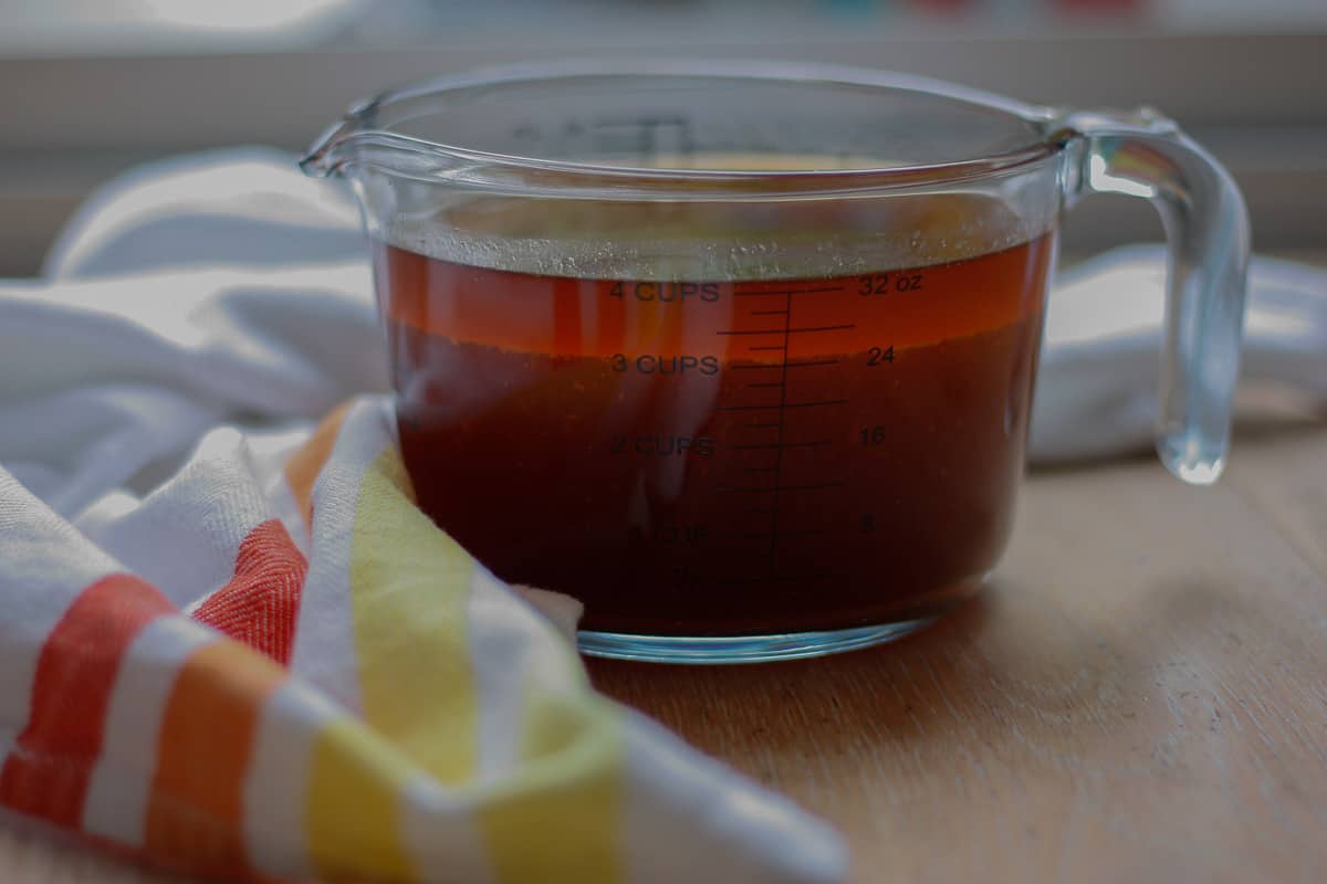 Pan juices in a glass measuring jug. The fatty layer can be seen at the top.