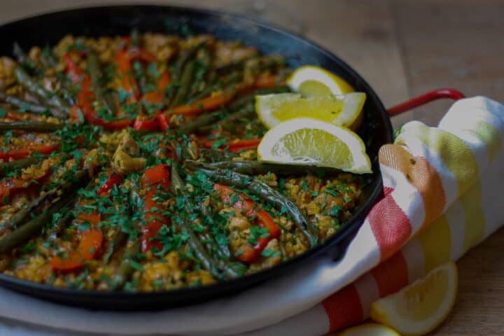 Cooked paella garnished with lemon wedges.