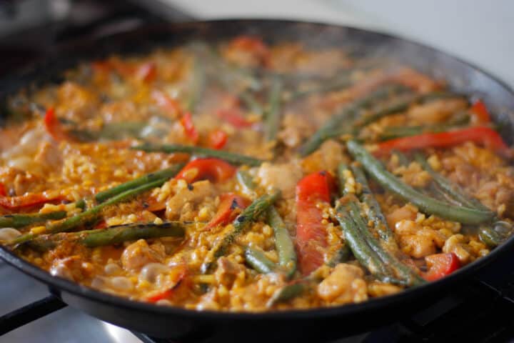 Stock bubbling in a pan around cooking paella.