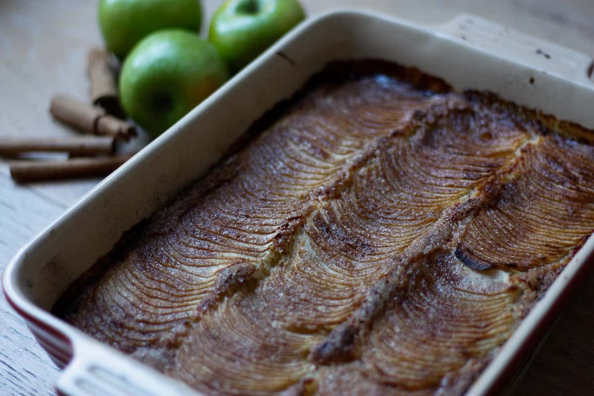 Finished cake in the baking dish. The apple slices are dark brown with cooked cinnamon sugar.