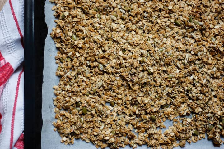 Cooked golden granola on a baking sheet line with baking paper'