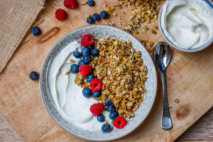 Nut-free granola served in a bowl with plain yoghurt and fresh berries.