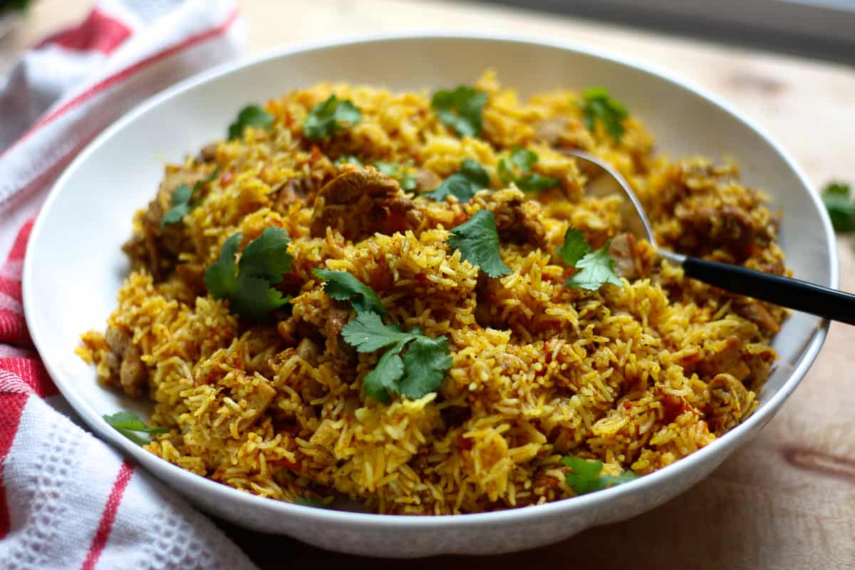 Finished pilau in a large shallow platter scattered with coriander leaves.