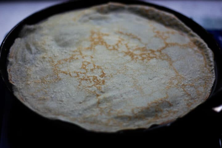 Lacey browned crepe in a black pan.