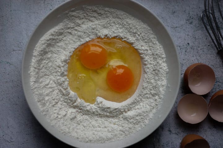 Eggs sitting in flour well before whisking,