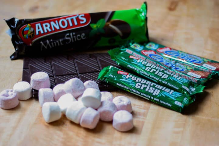 Mint Slice and Peppermint Crisp packets, with marshmallows and unwrapped slabs of dark chocolate.