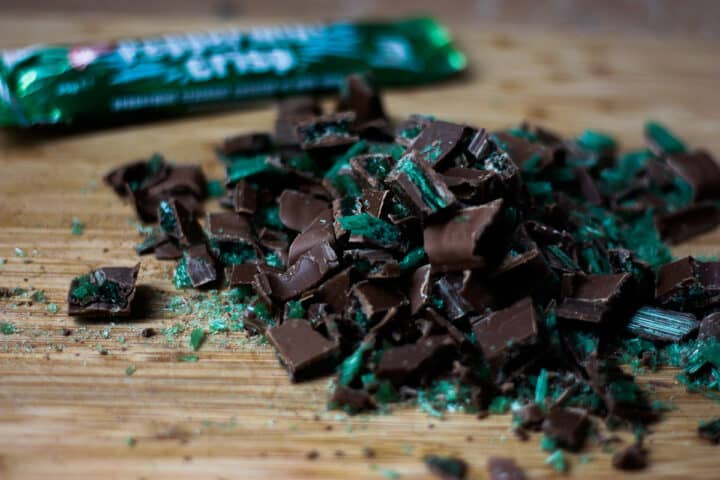 A pile of Peppermint Crisp rubble with the packet in the background - looks like green shattered glass and chocolate.