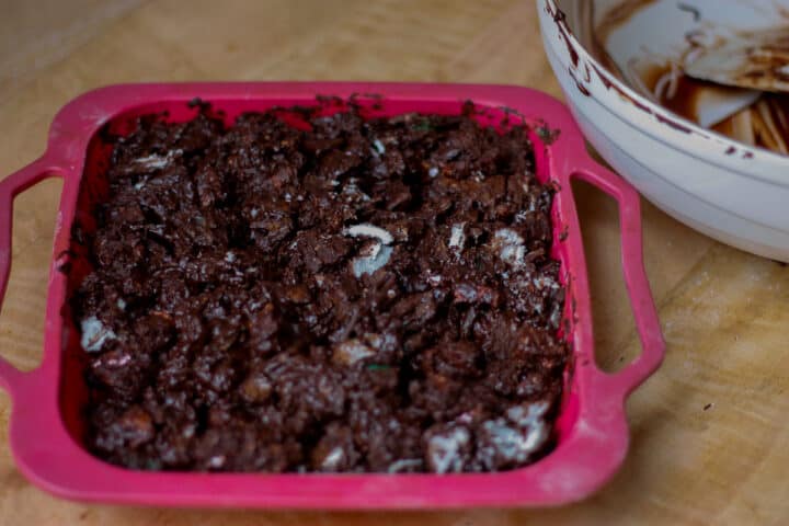 Chocolate rubble pressed into a red silicone tray ready for chilling.