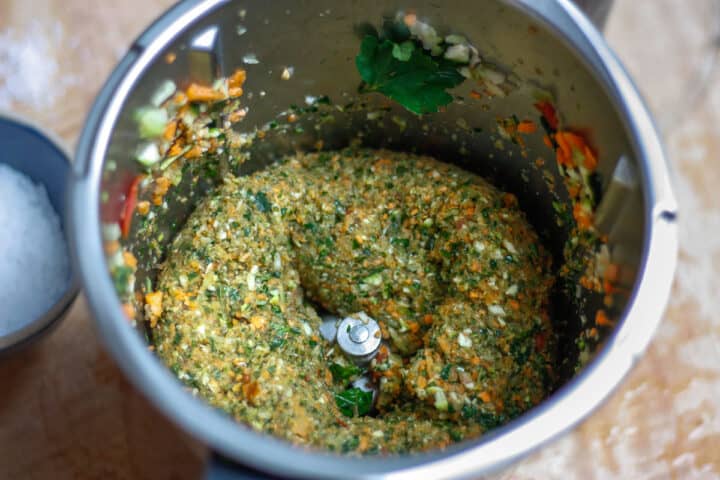 Looking down into a food processor bowl containing blended vegetable stock paste ingredients.