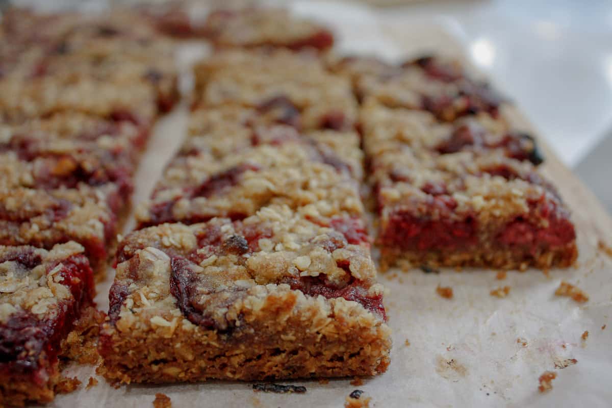 Side view of oat bites, showing edge of one and cut portion of another, the layer of raspberry visible.